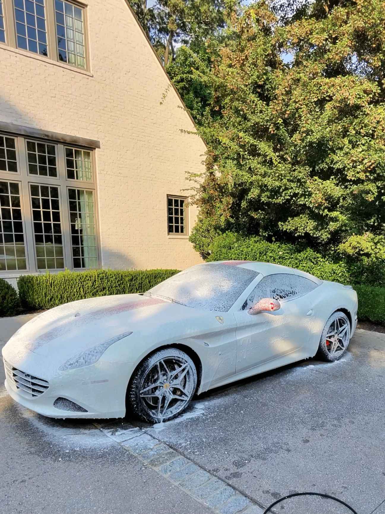 Foam applied to a red Ferrari during a professional hand wash